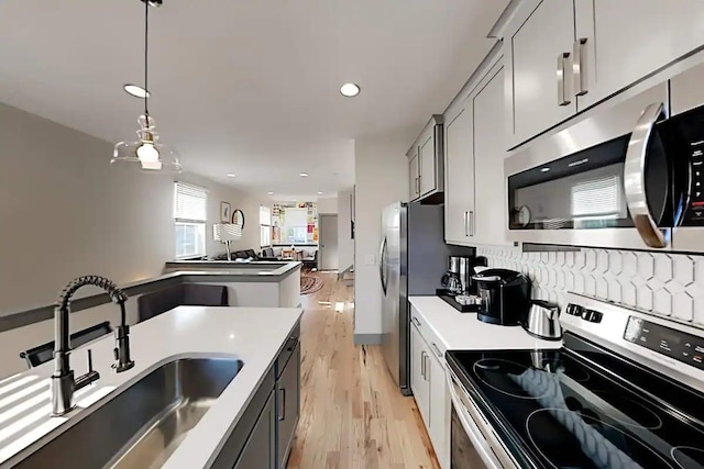 kitchen with stainless steel appliances, sink, hanging light fixtures, and gray cabinetry