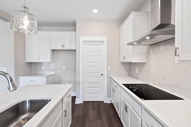 kitchen with pendant lighting, sink, white cabinets, black electric cooktop, and wall chimney exhaust hood