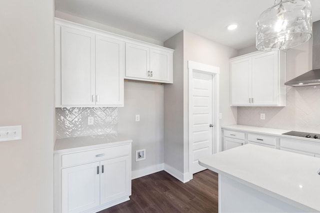 kitchen featuring wall chimney range hood, hanging light fixtures, black electric stovetop, white cabinets, and dark hardwood / wood-style flooring