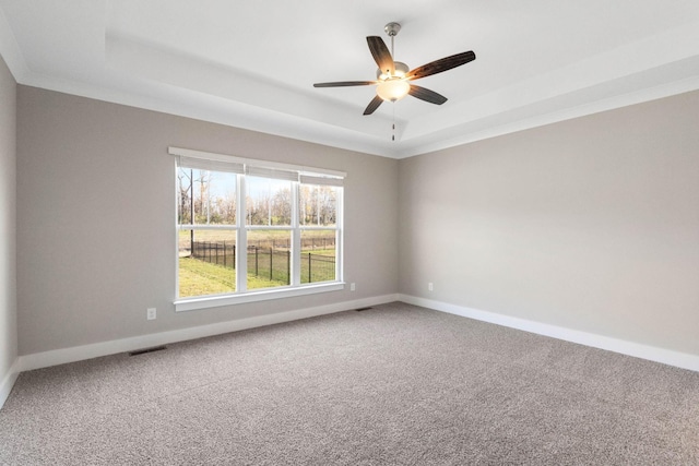 spare room with ceiling fan, a tray ceiling, and carpet floors