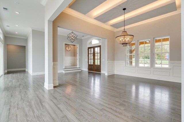 interior space with hardwood / wood-style flooring, crown molding, a chandelier, and french doors