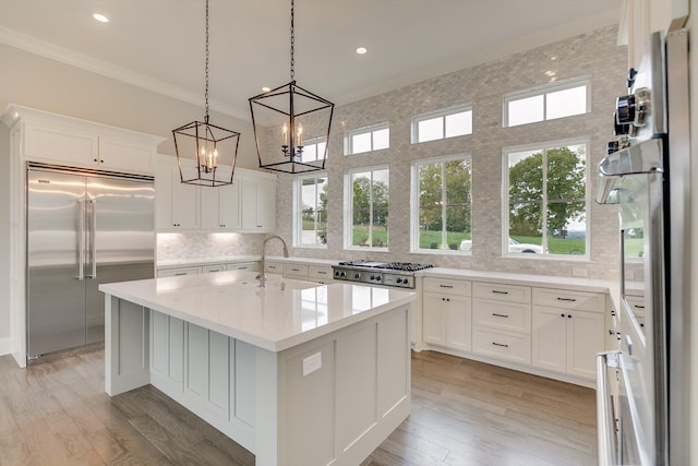 kitchen featuring stainless steel appliances, white cabinetry, sink, and a center island with sink