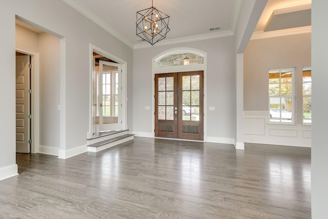 foyer with hardwood / wood-style floors, ornamental molding, french doors, and a chandelier