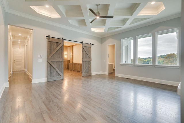 empty room featuring a barn door, coffered ceiling, hardwood / wood-style floors, and ceiling fan