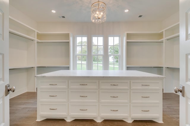 spacious closet with hardwood / wood-style floors and a notable chandelier