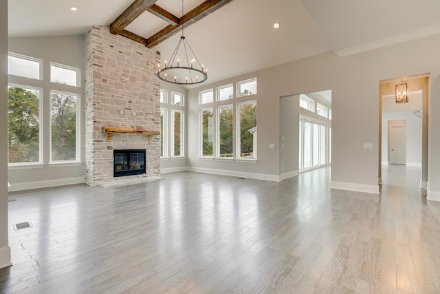 unfurnished living room with an inviting chandelier, high vaulted ceiling, a fireplace, beamed ceiling, and light wood-type flooring