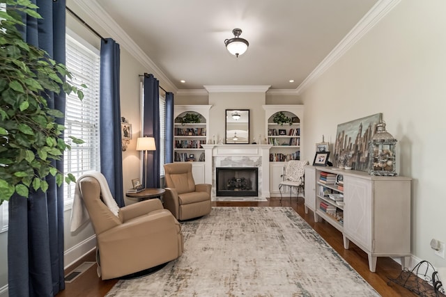 sitting room featuring crown molding, wood-type flooring, a high end fireplace, and built in features