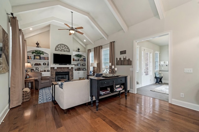 living room with beamed ceiling, ceiling fan, dark hardwood / wood-style flooring, and a brick fireplace