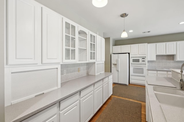 kitchen with white cabinetry, hanging light fixtures, white appliances, and decorative backsplash