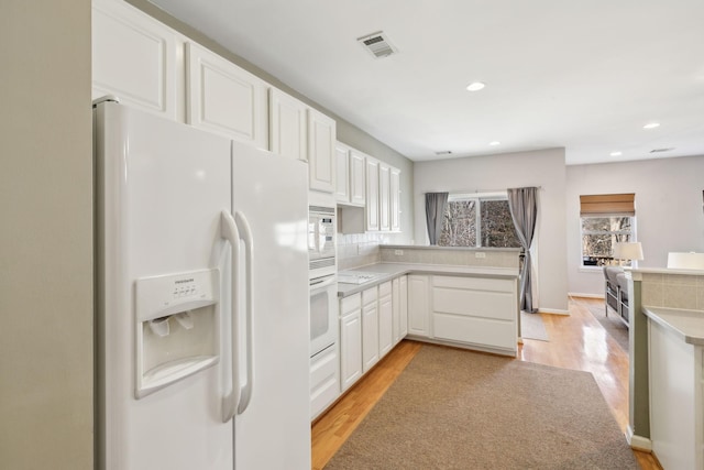 kitchen with white cabinets, white appliances, and light hardwood / wood-style floors