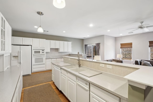 kitchen featuring sink, white appliances, white cabinetry, hanging light fixtures, and decorative backsplash