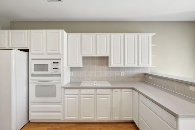 kitchen with backsplash, white appliances, light hardwood / wood-style flooring, and white cabinets