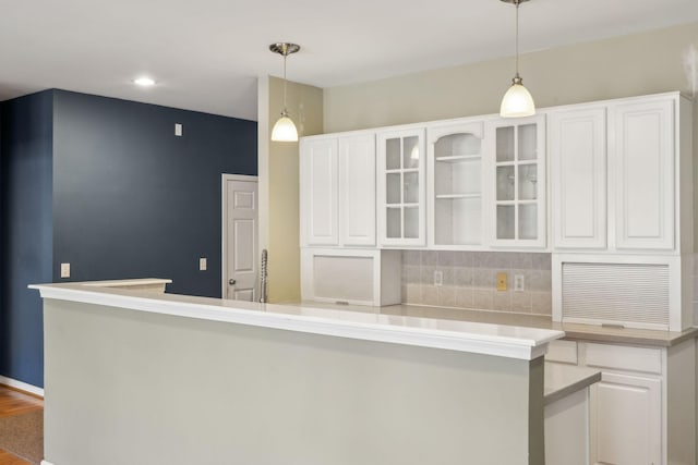 kitchen featuring pendant lighting, wood-type flooring, tasteful backsplash, and white cabinets