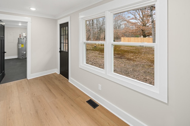 interior space with wood-type flooring, electric water heater, and ornamental molding