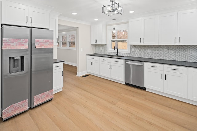 kitchen with white cabinetry, appliances with stainless steel finishes, sink, and decorative light fixtures