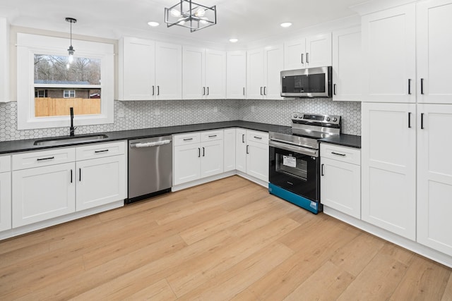 kitchen featuring hanging light fixtures, light wood-type flooring, white cabinets, and appliances with stainless steel finishes