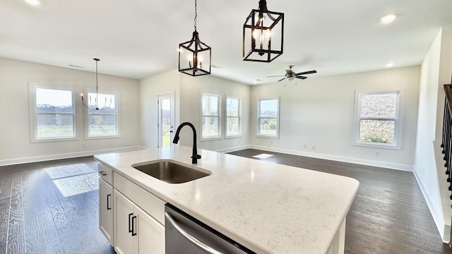 kitchen featuring sink, light stone countertops, an island with sink, white cabinets, and decorative light fixtures