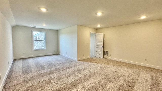 carpeted empty room with lofted ceiling