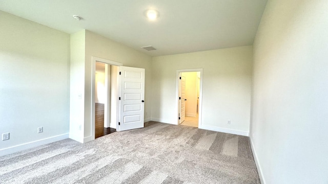 unfurnished bedroom featuring ensuite bathroom and light carpet