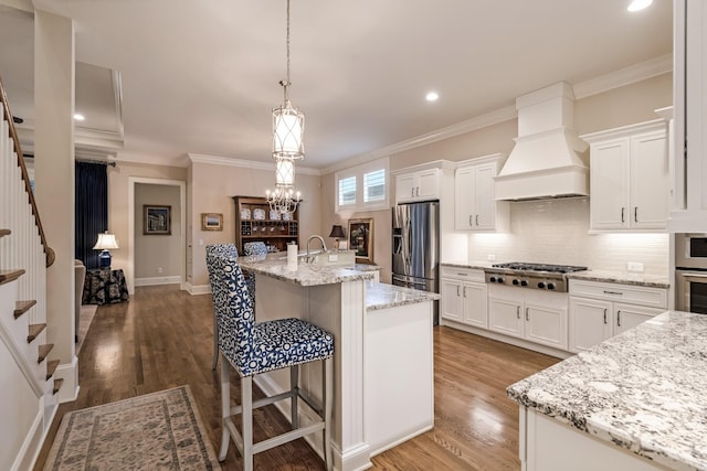 kitchen with custom exhaust hood, white cabinetry, and a kitchen island with sink