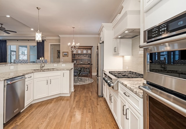 kitchen featuring stainless steel appliances, decorative light fixtures, sink, and white cabinets