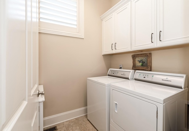 laundry area featuring light tile patterned floors, cabinets, and washing machine and clothes dryer