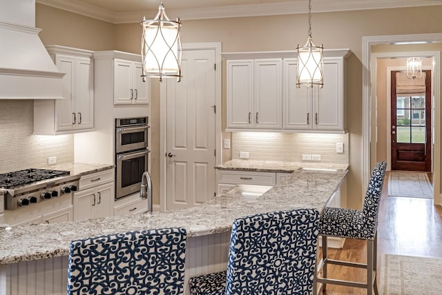 kitchen with white cabinetry, hanging light fixtures, a kitchen breakfast bar, and stainless steel appliances