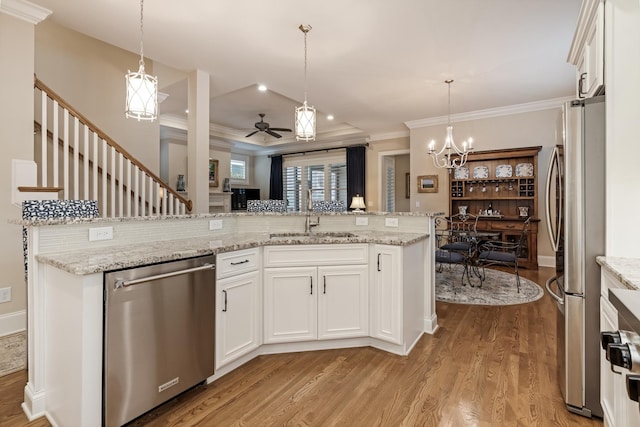 kitchen with white cabinetry, appliances with stainless steel finishes, sink, and decorative light fixtures