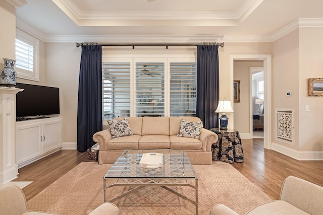 living room with crown molding, a tray ceiling, and hardwood / wood-style flooring