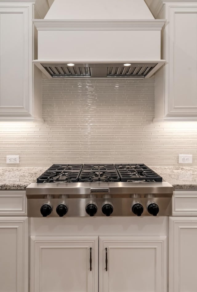 kitchen with light stone counters, stainless steel gas cooktop, custom exhaust hood, and white cabinets