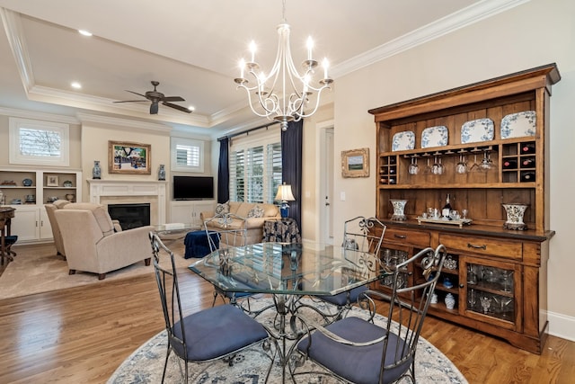 dining space with crown molding, ceiling fan with notable chandelier, and light hardwood / wood-style floors