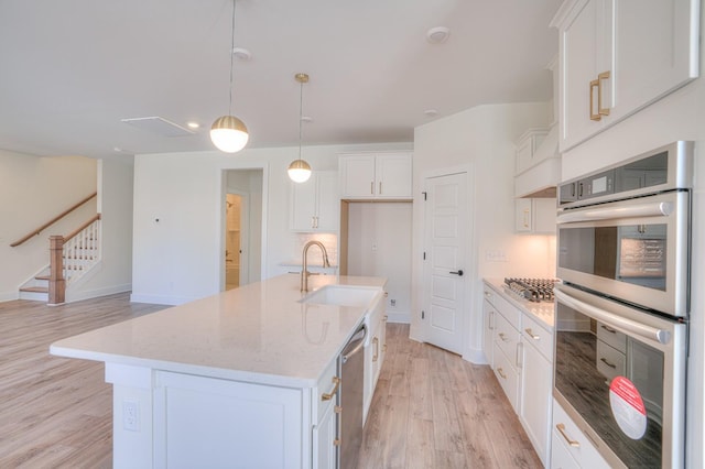 kitchen with white cabinetry, stainless steel appliances, a kitchen island with sink, and pendant lighting