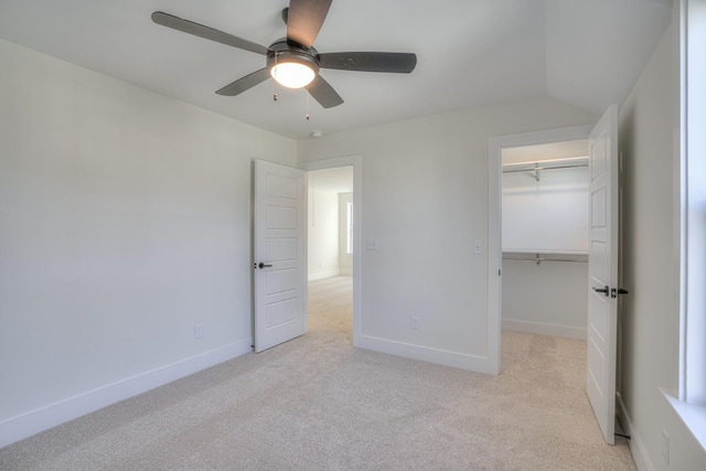 unfurnished bedroom featuring a spacious closet, light carpet, ceiling fan, and a closet