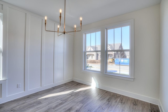 unfurnished dining area with light hardwood / wood-style flooring and a notable chandelier