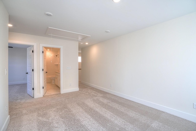 unfurnished bedroom featuring ensuite bathroom, a walk in closet, and light carpet