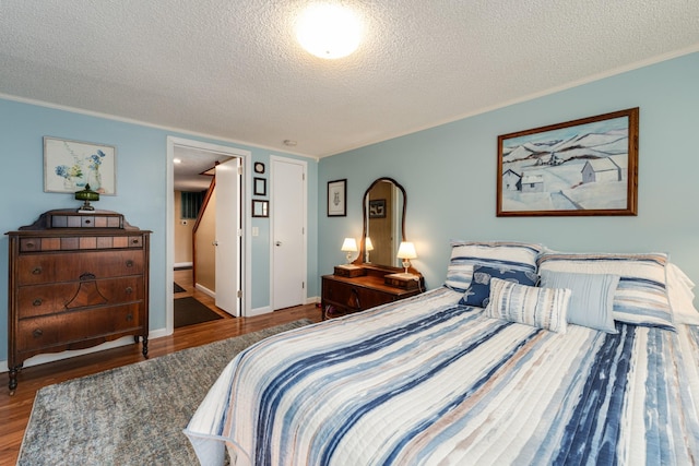 bedroom with wood-type flooring, ornamental molding, and a textured ceiling