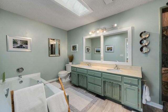 bathroom with toilet, a skylight, a textured ceiling, vanity, and hardwood / wood-style flooring