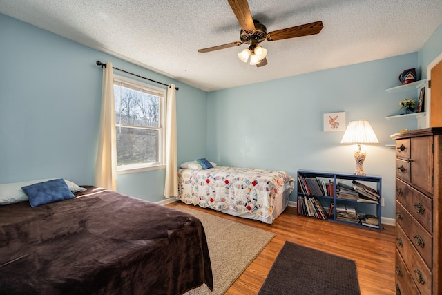 bedroom with ceiling fan, light hardwood / wood-style flooring, and a textured ceiling