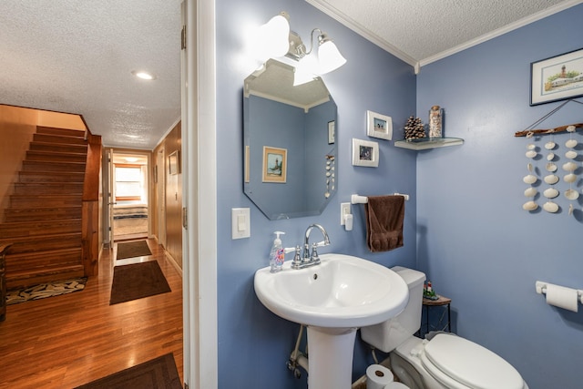 bathroom featuring crown molding, toilet, a textured ceiling, and hardwood / wood-style flooring