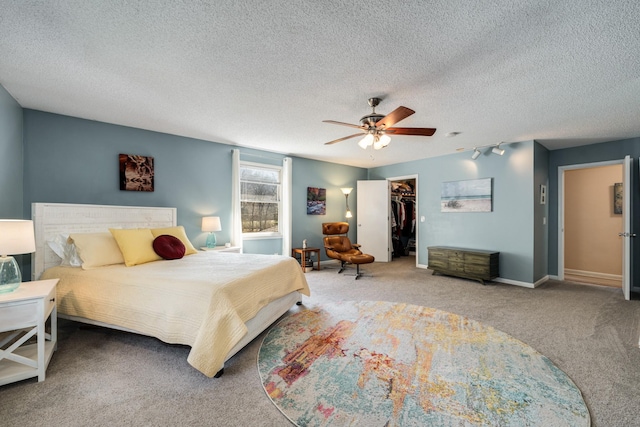 bedroom featuring ceiling fan, carpet floors, a textured ceiling, a walk in closet, and a closet