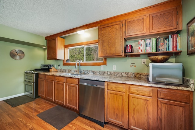 kitchen featuring sink, light hardwood / wood-style flooring, a textured ceiling, and appliances with stainless steel finishes