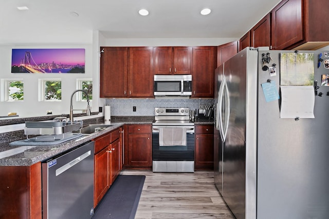 kitchen with sink, decorative backsplash, kitchen peninsula, stainless steel appliances, and light hardwood / wood-style flooring