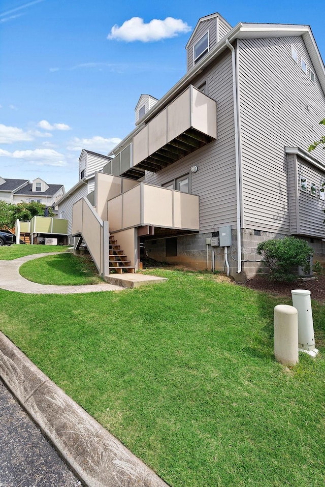 view of side of home featuring a balcony and a yard