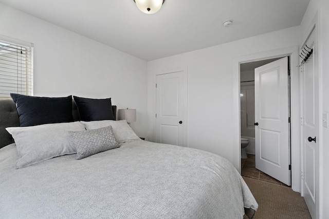 bedroom with ensuite bathroom and dark carpet