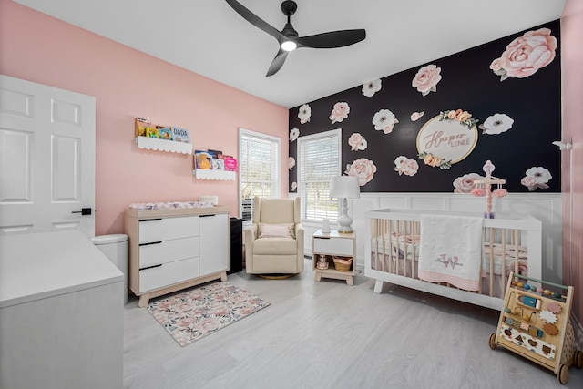 bedroom featuring a ceiling fan, a crib, and wood finished floors