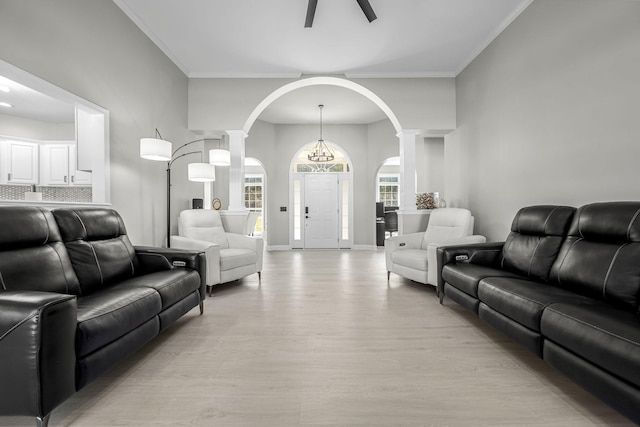 living room featuring baseboards, crown molding, light wood-style flooring, and ornate columns