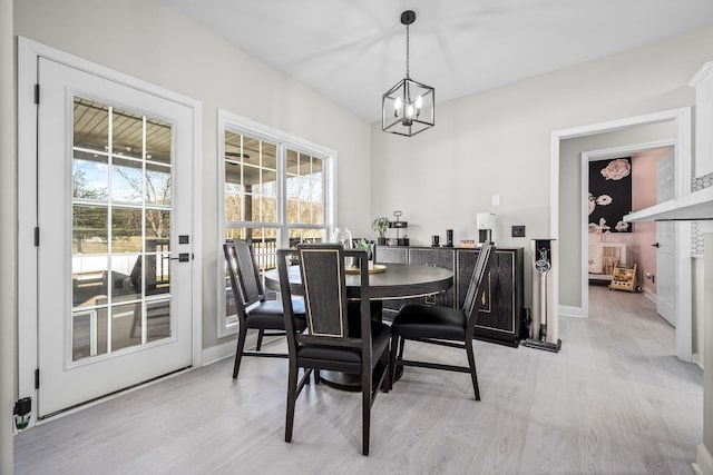 dining room with light wood-style floors, baseboards, and a notable chandelier