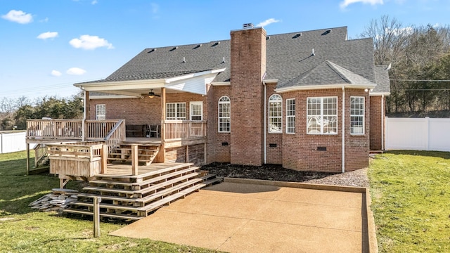 rear view of property with a lawn, a chimney, fence, a deck, and brick siding