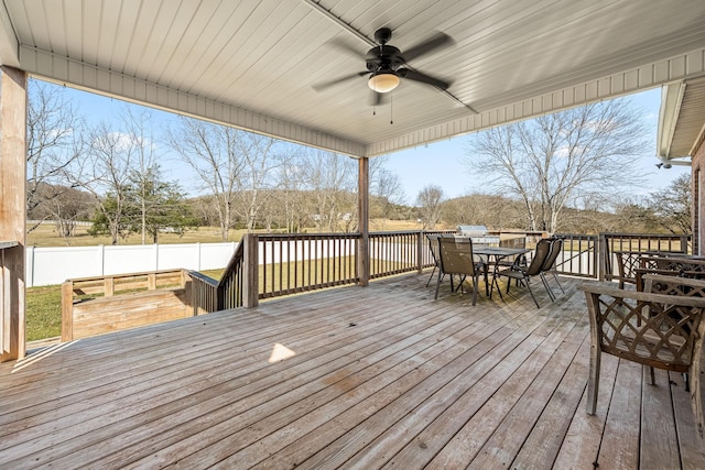 wooden deck with outdoor dining area and a ceiling fan