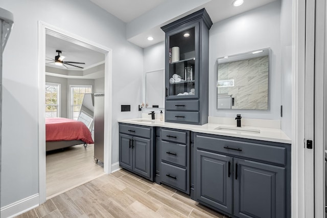 full bath featuring double vanity, recessed lighting, connected bathroom, a sink, and wood finished floors